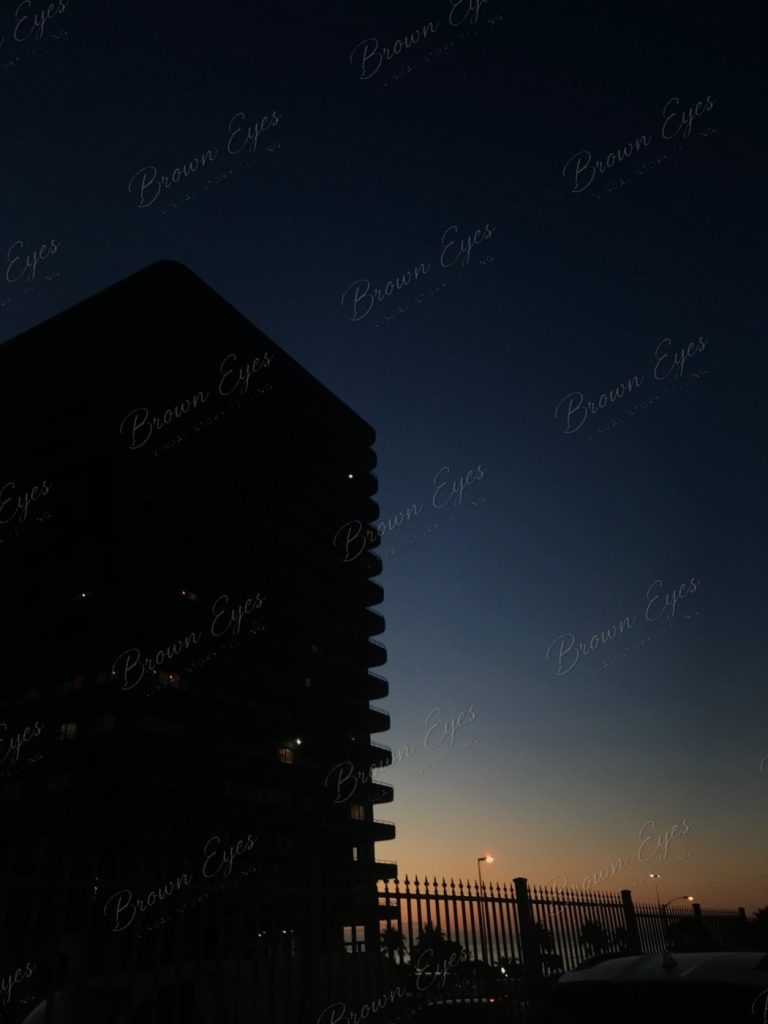 A dark building at night with a few small lights still burning inside